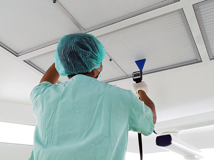 Person in protection attire performing HEPA filter installation leak test
