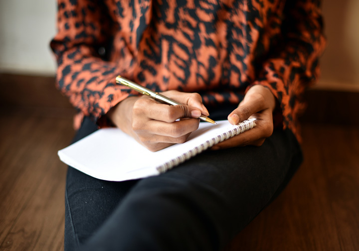 Close up of a hand making notes on a pad. 