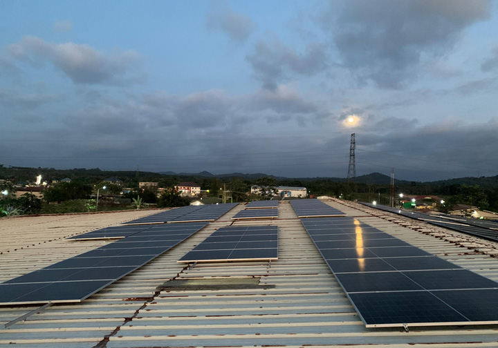 Rooftop solar panels with a darkening sky in the background. 