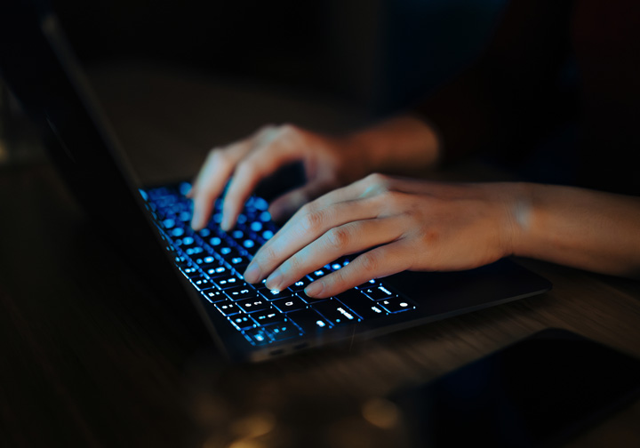 Hands typing on a laptop keyboard. 