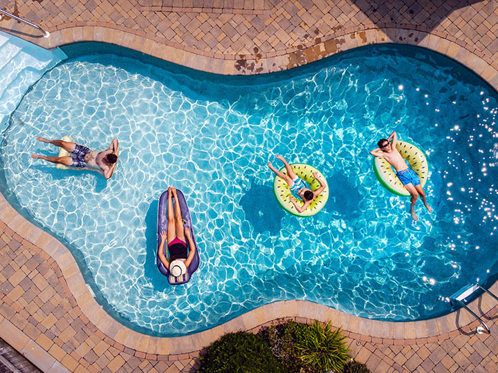 Aerial view of a family with a mother, father and two sons, floating in pool on a summer day