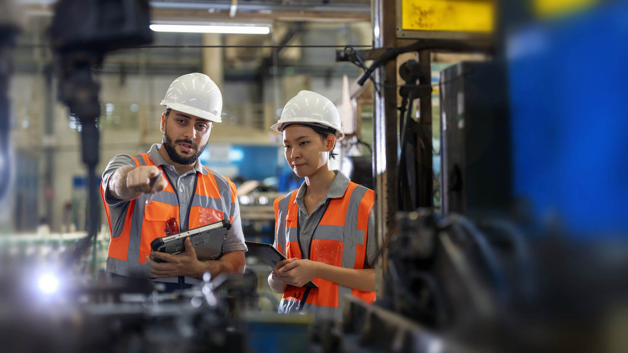 Senior Industrial engineer explaining the Robotic arms Welding unit functioning to new engineer. Car auto part manufacturing industry. Production quality control process. Maintenance of manufacturing equipment.